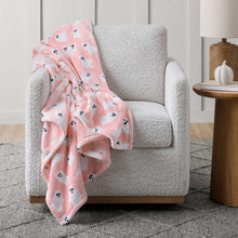 Pink Halloween ghost lounge throw blanket draped over a light gray armchair
