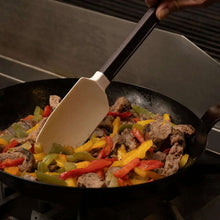 Silicone scraper serving mixed vegetables and meat from a skillet