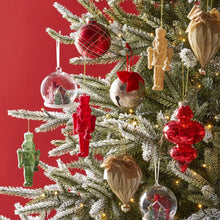 Assorted holiday keepsake ornaments on a Christmas tree, in red, green, and gold