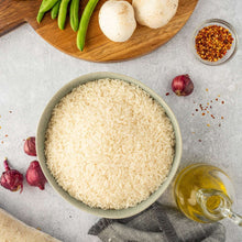 Bowl of uncooked long grain rice with oil, onion, and herbs