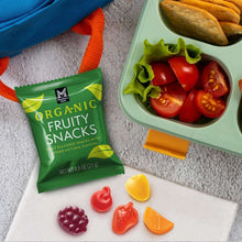 Green organic fruity snacks pouch with assorted fruit-shaped snack pieces on tray
