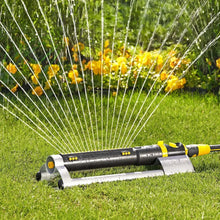 Oscillating lawn sprinkler on grass with water arc spray from rotating nozzles