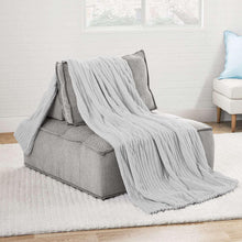 Oversized plush blanket in light gray with vertical ribbed texture, draped on sofa