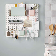 White pegboard organizer board with drawers, hooks, and office accessories
