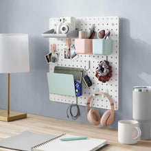 White pegboard organizer board with hanging bins and hooks