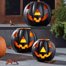Three black metal jack-o-lantern lanterns with orange triangular eyes and jagged smiles