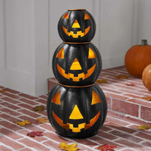 Three black metal jack-o-lantern decor pieces with orange carved face cutouts
