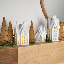 Pre-lit holiday village set with lit houses and brown pine trees