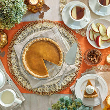 Pumpkin pie on a plate with apple slices and cinnamon sticks nearby.
