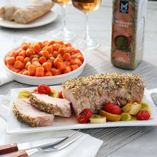 Rosemary leaves seasoning bottle on table beside roast meat and vegetables