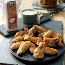 Sea salt bottle next to seasoned chicken wings on tray