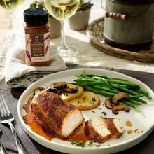 Seasoned pork with apple slices, mushrooms, herbs, and green asparagus on plate