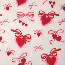 Lounge throw fabric close-up with red hearts and bows on white