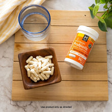 Probiotic capsules bottle with orange label and white capsules in wooden dish