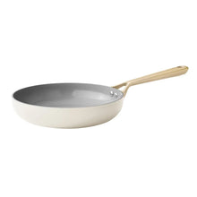Cream ceramic frying pan with dark interior and gold-tone handle