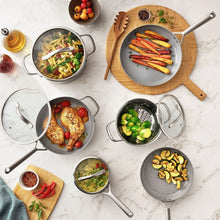 Stainless steel pots and covered skillet with dark lids, ceramic-coated cooking surface