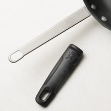 Nonstick fry pan with black handle end and metal pan body, showing riveted connection