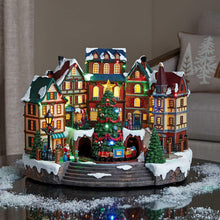 Pre-lit musical village display with mini houses, lit tree, and merry-go-round base
