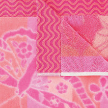 Pink kids beach towel close-up with swirling wave pattern and large heart motifs
