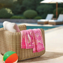Pink floral kids beach towel draped over a wicker lounge chair
