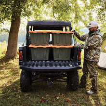 Open heavy-duty storage tote with orange lid panels and dark gray base on trailer