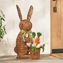 Woven bunny porch decoration with spring flowers, pastel eggs, and a carrot in wicker
