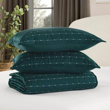 Teal quilt set includes three folded layers and two patterned pillow shams with stitched lines