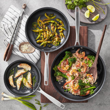 Hard anodized fry pan set with three nonstick pans holding cooked meals