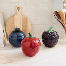 Stoneware berry canister set, three lidded canisters in blue, red, and purple with stems.