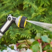 Watering hose sprayer gun with yellow nozzle spraying a fine mist