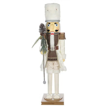 Wooden nutcracker decoration in white uniform, blue hat, holding pine branch and cane.