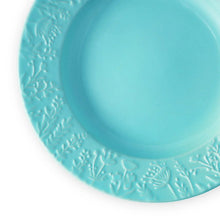 Blue ceramic salad plate, close-up of embossed floral border around the rim
