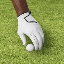 White golf glove on grass with black wrist strap and perforated finger panels