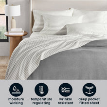 White sheet set with thin gray stripe print, styled on a bed with pillowcases