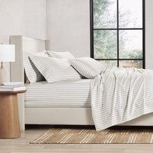 White sheet set with thin gray stripe print on a bed with matching pillowcases