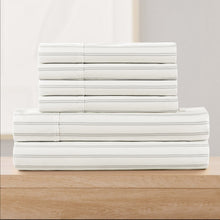 White sheet set with thin gray stripe print, stacked flat on a wood surface