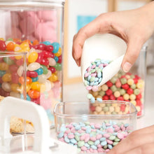Hand adding candy into an open clear flip-lock container among other filled bins