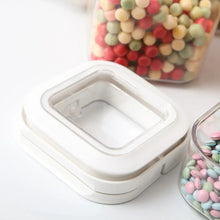 Flip-lock container base with clear lid, holding pastel candy pieces