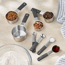 Stainless steel measuring cups and spoon set with dark handles, multiple sizes