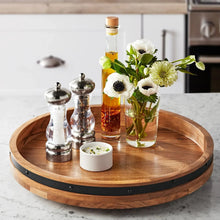 Acacia wood lazy Susan turntable with black rim, holding bottles, bowls, and flowers