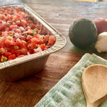 Foil steam table pan filled with diced vegetables on prep counter