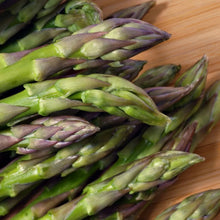 Asparagus spears on wood board, green stalks with purple-tinged heads