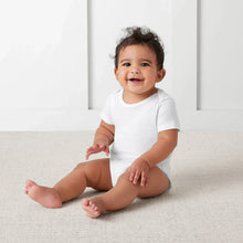 White short-sleeve baby bodysuit with snap closures, worn on a crawling infant