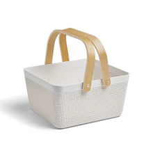 White woven basket with perforated pattern and light wood handles, open top.