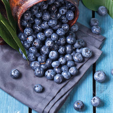 Blueberries in a wooden scoop on a cloth with scattered berries