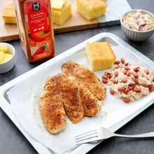 Cajun seasoning bottle beside cooked fish and rice on a serving plate
