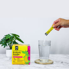 Probiotic powder stick being opened above a glass of water