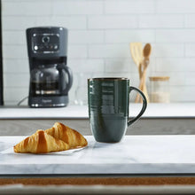 Green coffee mug with a croissant on a countertop