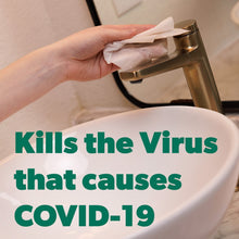 Hand wiping a toilet surface with a disinfecting wipe