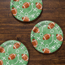 Assorted football-pattern paper plates with green design, footballs, arrows, and Xs